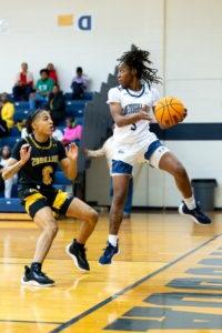 Female 分 Basketball player jumping while catching basketball and defending against opponent